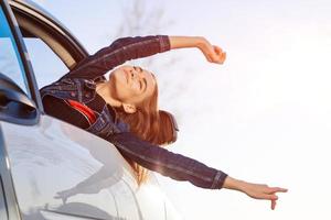 To adventure. Girl is resting and enjoying journey. Happy girl rides in car put photo