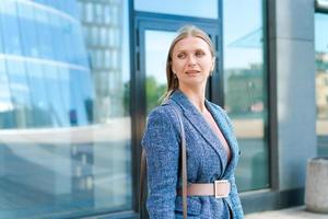 Portrait business woman smiling outdoors in business clothes against backdrop photo