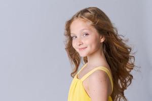 Happy half-length school age girl portrait in yellow clothes with long wavy photo