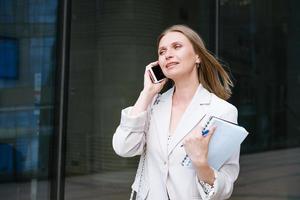Successful businesswoman or businesswoman taking notes and talking on cell phone while walking outdoors. Business woman photo