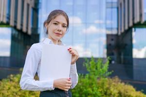 elegante caucásico negocio mujer en formal vestir sostiene papel documentos en su foto