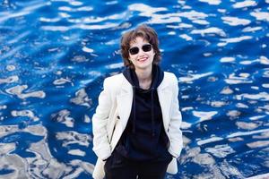 Portrait smiling happy girl in sunglasses, in black sweatshirt and white coat photo