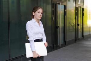 Portrait young business woman with smile with laptop in her hands stands photo