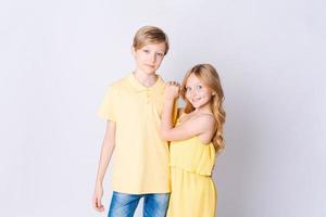 Two happy children standing near an empty gray background and hugging cute photo