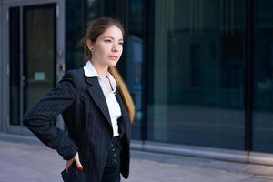 Business woman in suit uses smartphone. Big city with skyscrapers in background. Talking on the phone during the day photo