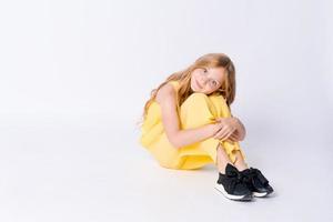 Studio portrait pretty girl with curly hair sitting on floor in studio smiling photo