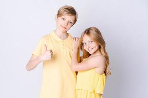 Two happy children standing near an empty gray background and hugging cute photo