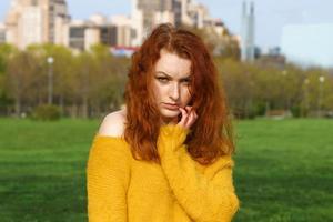 Gorgeous happy redhead woman sitting on beaton and grass relaxing in local park photo