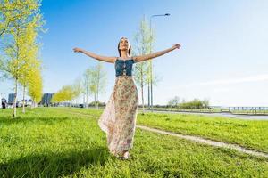 Attractive happy young woman long flowered dress flying her hair enjoying free photo