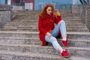 young woman in a red coat posing in spring on a footbridge photo