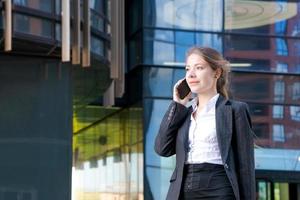 Business woman in suit uses smartphone. Big city with skyscrapers photo