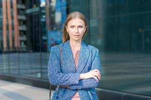 Successful business woman smiling, happy with arms crossed arms in city against photo