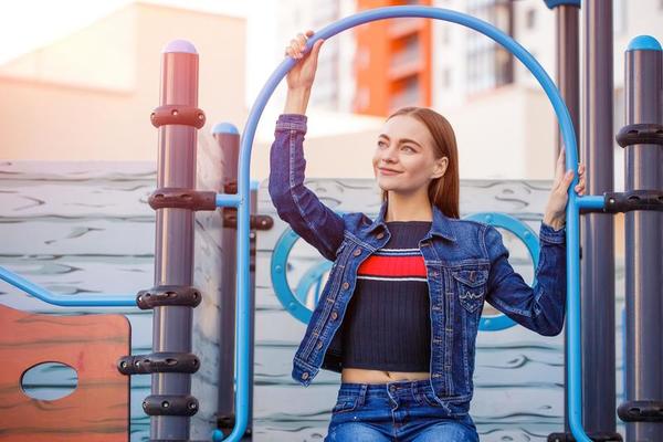 A cute girl is sitting on playground. Happy caucasian girl in blue denim  jacket 21605012 Stock Photo at Vecteezy