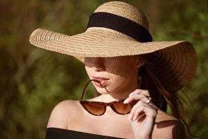 joven mujer en Paja sombrero de cerca en Gafas de sol foto