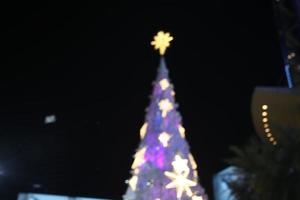 blur bokeh snow christmas tree with night sky background and building photo