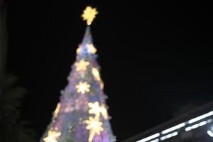 blur bokeh snow christmas tree with night sky background and building photo