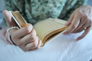 Muslim women's hand reading quran at night photo