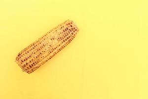 corn cob on yellow background close up photo