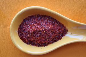 top view of chili flakes on a spoon on orange background photo