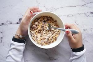 top view of child hand eating cereal breakfast photo