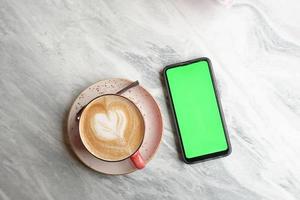 cpu of coffee and mart phone with green screen on table photo