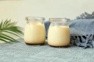 Caramel pudding in a glass jar on table photo