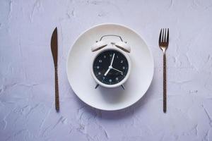 Alarm clock on plate on wooden table, top view. photo