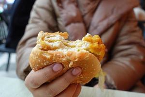 hand holding beef burger on table close up photo