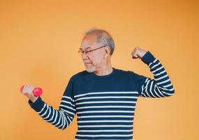 Senior male with dumbbell for exercise active lifestyle in retirement life health care on color background. photo