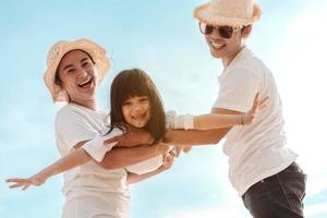 Happy asian family enjoy the sea beach at consisting father, mother and daughter having fun playing beach in summer vacation on the ocean beach. Happy family with vacations time lifestyle concept. photo