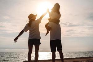 Happy asian family enjoy the sea beach at consisting father, mother and daughter having fun playing beach in summer vacation on the ocean beach. Happy family with vacations time lifestyle concept. photo