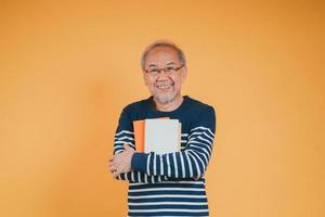 Happy positive senior male smiling and read book education knowledge learning on color background. photo