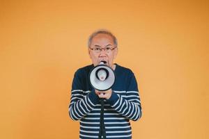 Senior male shouting with megaphone for announce news or discount sale shopping on color background. photo
