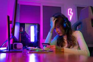 Top up online game with credit card concept. Gamer and E-Sport online of Asian woman playing online computer video game with lighting effect, broadcast streaming live at home. Gamer and E-Sport gaming photo