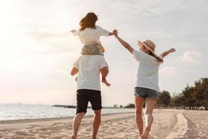 Happy asian family enjoy the sea beach at consisting father, mother and daughter having fun playing beach in summer vacation on the ocean beach. Happy family with vacations time lifestyle concept. photo