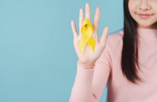 happy woman holding yellow ribbon, september, suicide prevention day, childhood, sarcoma, bone and bladder cancer Awareness month, health care support people and world cancer day concept photo