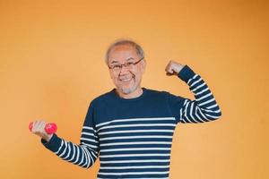 Senior male with dumbbell for exercise active lifestyle in retirement life health care on color background.