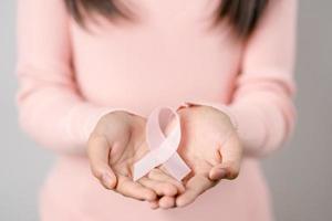 woman hands holding pink ribbon, Breast cancer awareness, world cancer day, national cancer survivor day in february concept. photo