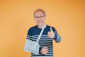 Arm broken. Senior male sling support hand confident smile broken after accident wear arm splint for treatment show good sign. health insurance on mobile concept. photo