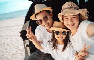 contento asiático familia en el playa en día festivo. de el familia tomar un selfie.ellos son teniendo divertido jugando disfrutando en el playa. verano familia y estilo de vida. foto