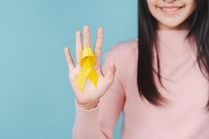 happy woman holding yellow ribbon, september, suicide prevention day, childhood, sarcoma, bone and bladder cancer Awareness month, health care support people and world cancer day concept photo