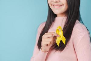 happy woman holding yellow ribbon, september, suicide prevention day, childhood, sarcoma, bone and bladder cancer Awareness month, health care support people and world cancer day concept photo