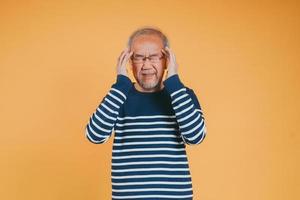 Asian senior man feeling headache or migraine pain on the yellow background. photo