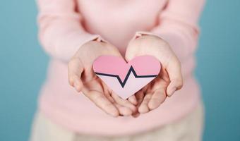 woman holding heart anatomy paper cut, heart attack, heart disease, Female with health care and Healthy feminine, World Heart Day concept. photo