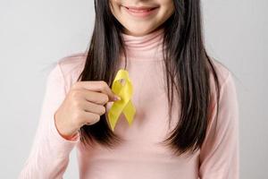 happy woman holding yellow ribbon, september, suicide prevention day, childhood, sarcoma, bone and bladder cancer Awareness month, health care support people and world cancer day concept photo