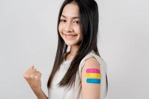 Happy young woman show victory sign after getting a vaccine. showing shoulder with bandage after receiving vaccination, herd immunity, side effect, booster dose, vaccine passport and Coronavirus photo