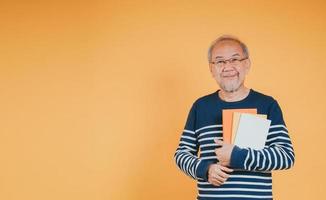 Happy positive senior male smiling and read book education knowledge learning on color background. photo