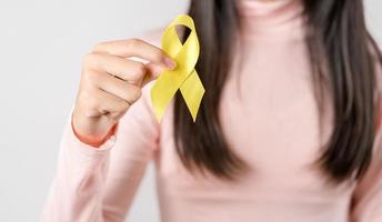 happy woman holding yellow ribbon, september, suicide prevention day, childhood, sarcoma, bone and bladder cancer Awareness month, health care support people and world cancer day concept photo