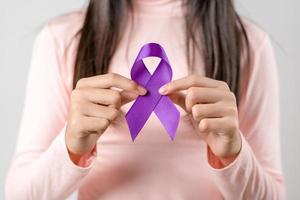 mujer manos participación púrpura cinta, Alzheimer enfermedad, pancreático cáncer, epilepsia conciencia, mundo cáncer día en un púrpura de colores fondo, mundo cáncer día concepto foto