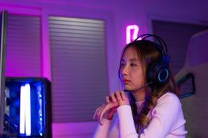 Wrist pain concept. Gamer and E-Sport online of Asian woman playing online computer video game with lighting effect, broadcast streaming live at home. her use her wrist for a long time. photo